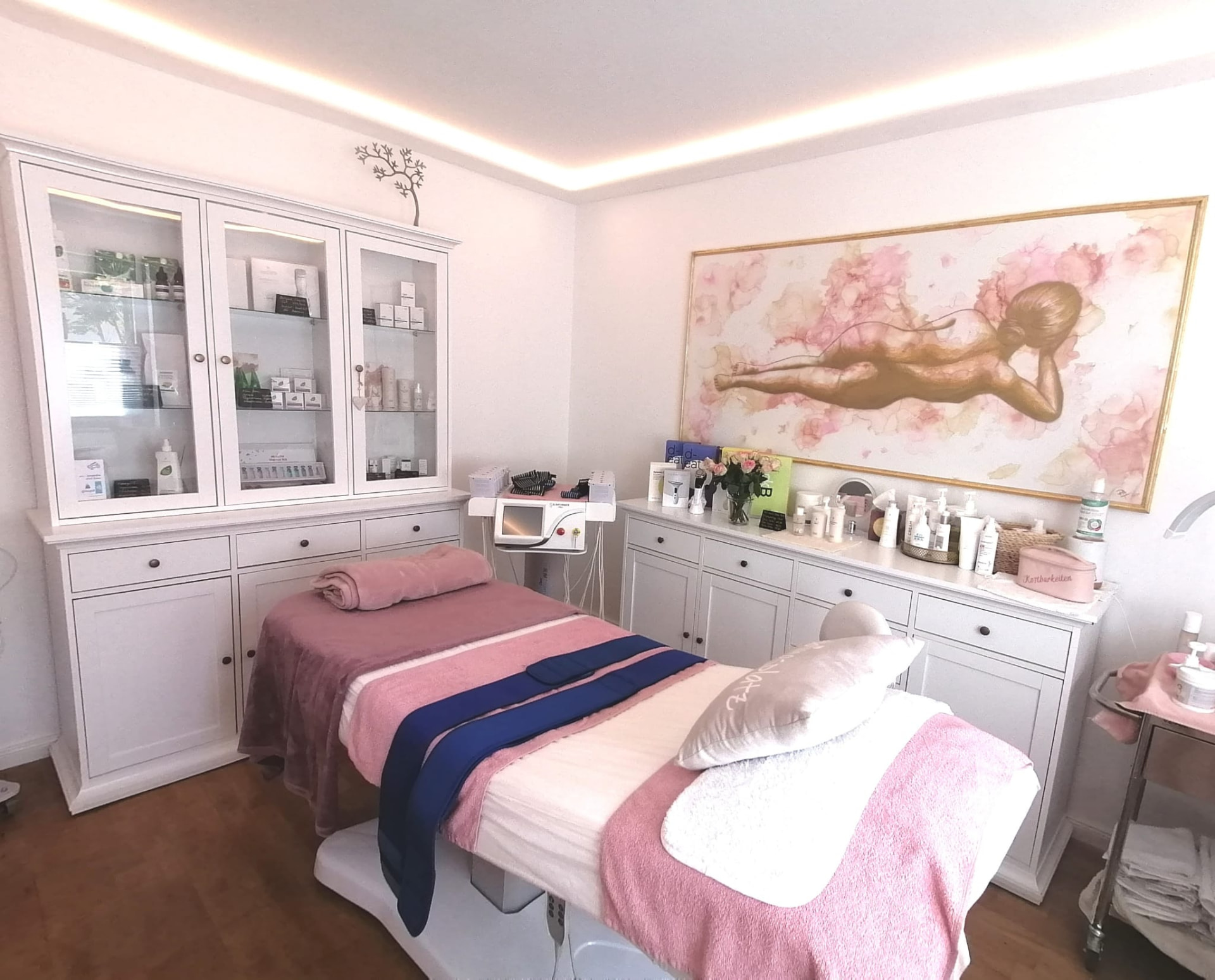 Behandlungsraum mit Liege, Sideboard und Wandbild im Hautschön Studio